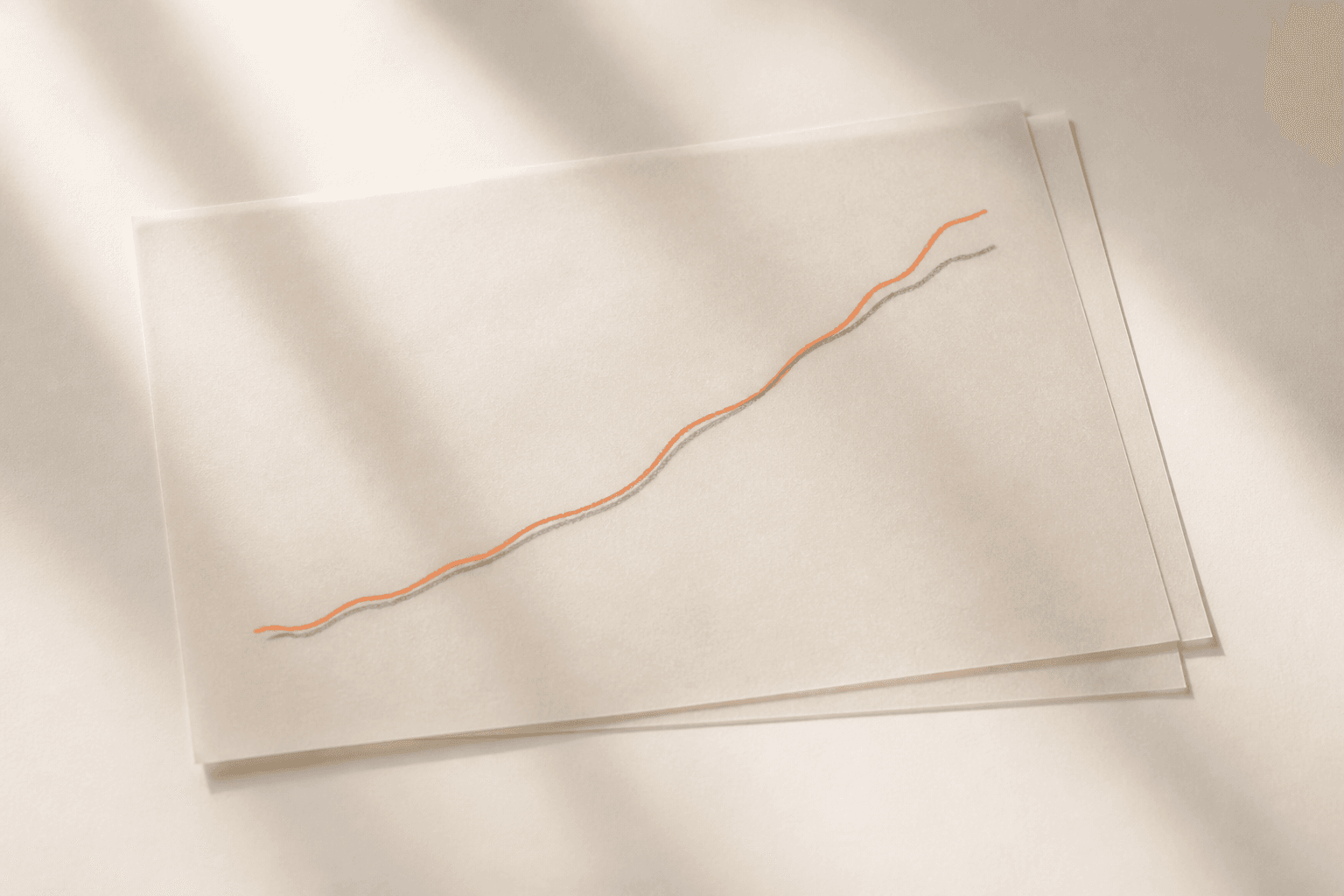 Two sheets of translucent tracing paper on a warm off-white surface, each bearing a simple hand-drawn rising line, laid one over the other so the two curves read as a single line.